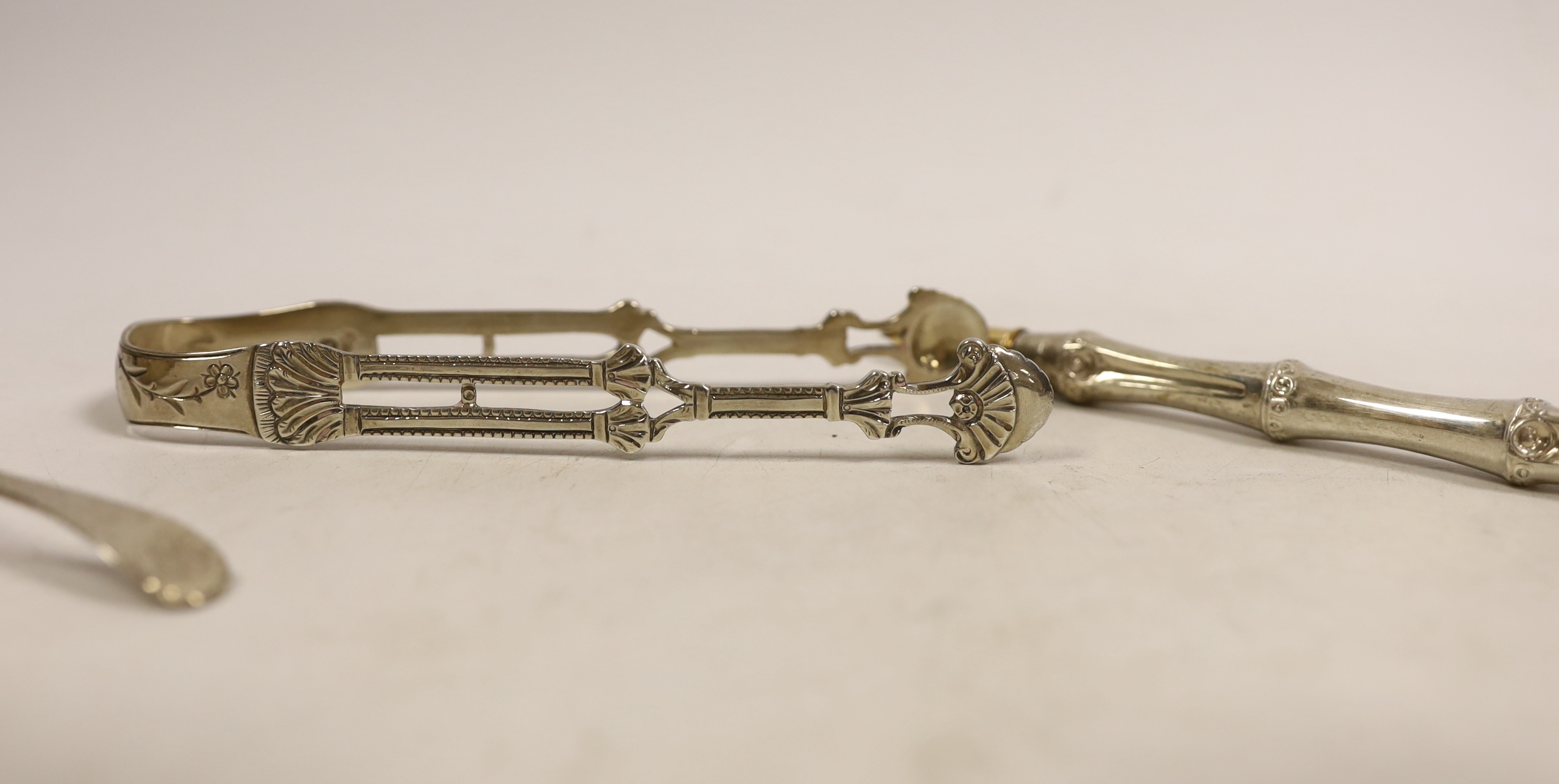 A George III silver bright cut engraved caddy spoon, Walter Brind, London 1785, 91mm, a pair of Georgian silver sugar tongs and two pens.